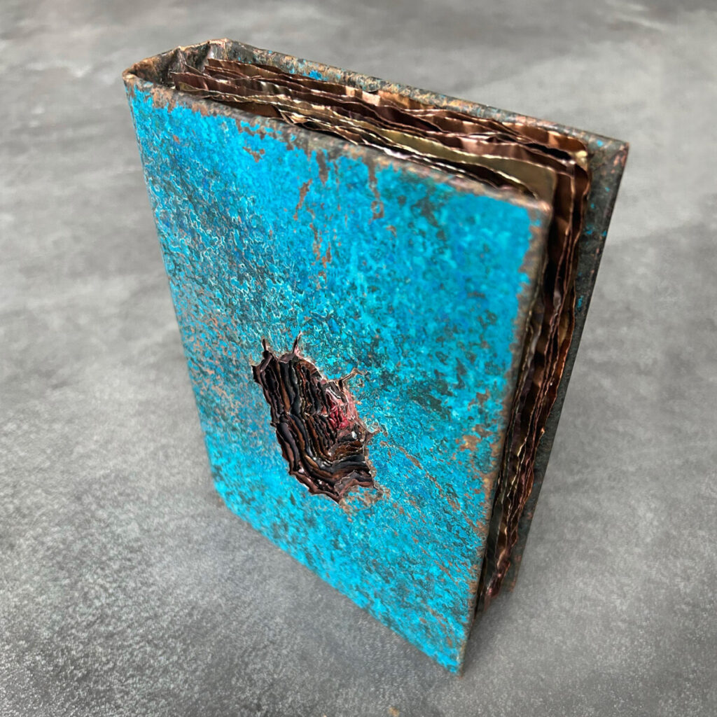 Dangerous Knowledge stood on edge, showing the turquoise cover and the deep wound cut into it