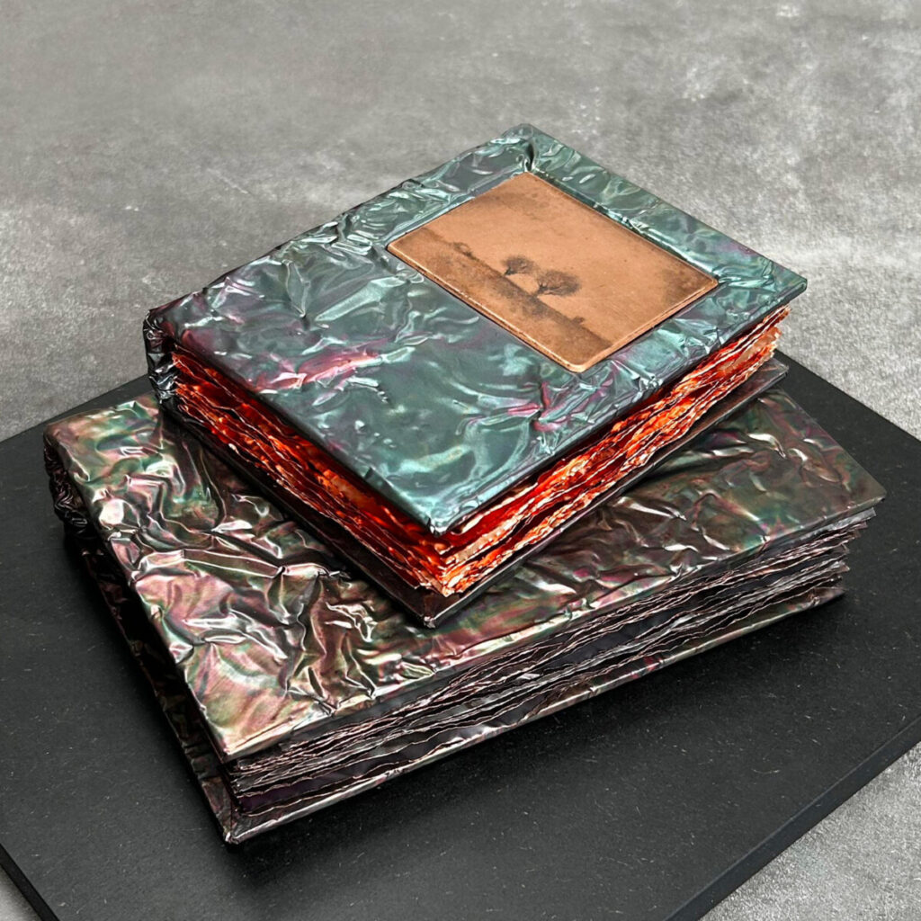 Two Unforgettable Seasons, two stacked copper books in teal and green patina, the top one inset with a Gunnar Norrman drypoint plate