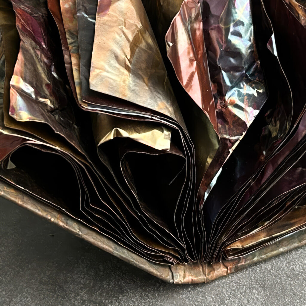 Closeup of The Unstoppable Story, layered copper pages erupting in all directions