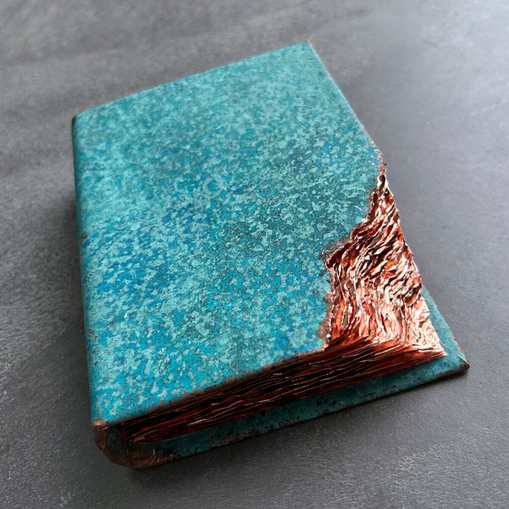 Wilderness Survival Manual, a patinated copper artist's book with a turquoise cover, shown closed